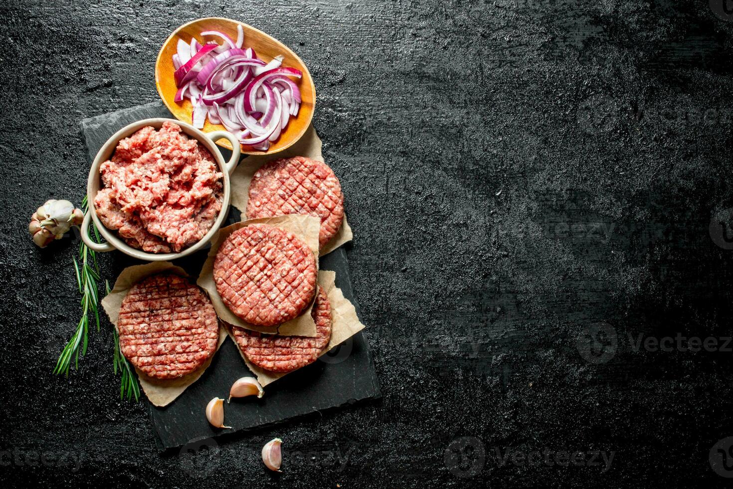 Raw burgers with ground beef and sliced onions in bowls. photo