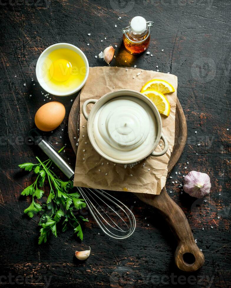 Mayonnaise on a cutting Board with greens, eggs and oil. photo