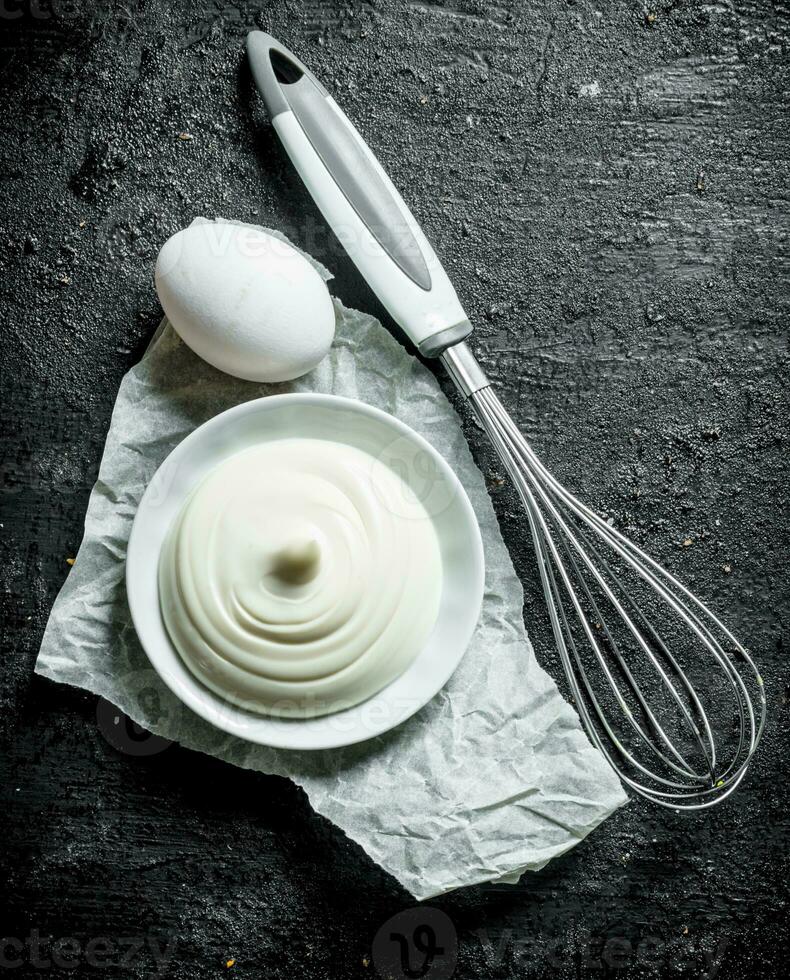 Mayonnaise in a plate on paper with egg. photo