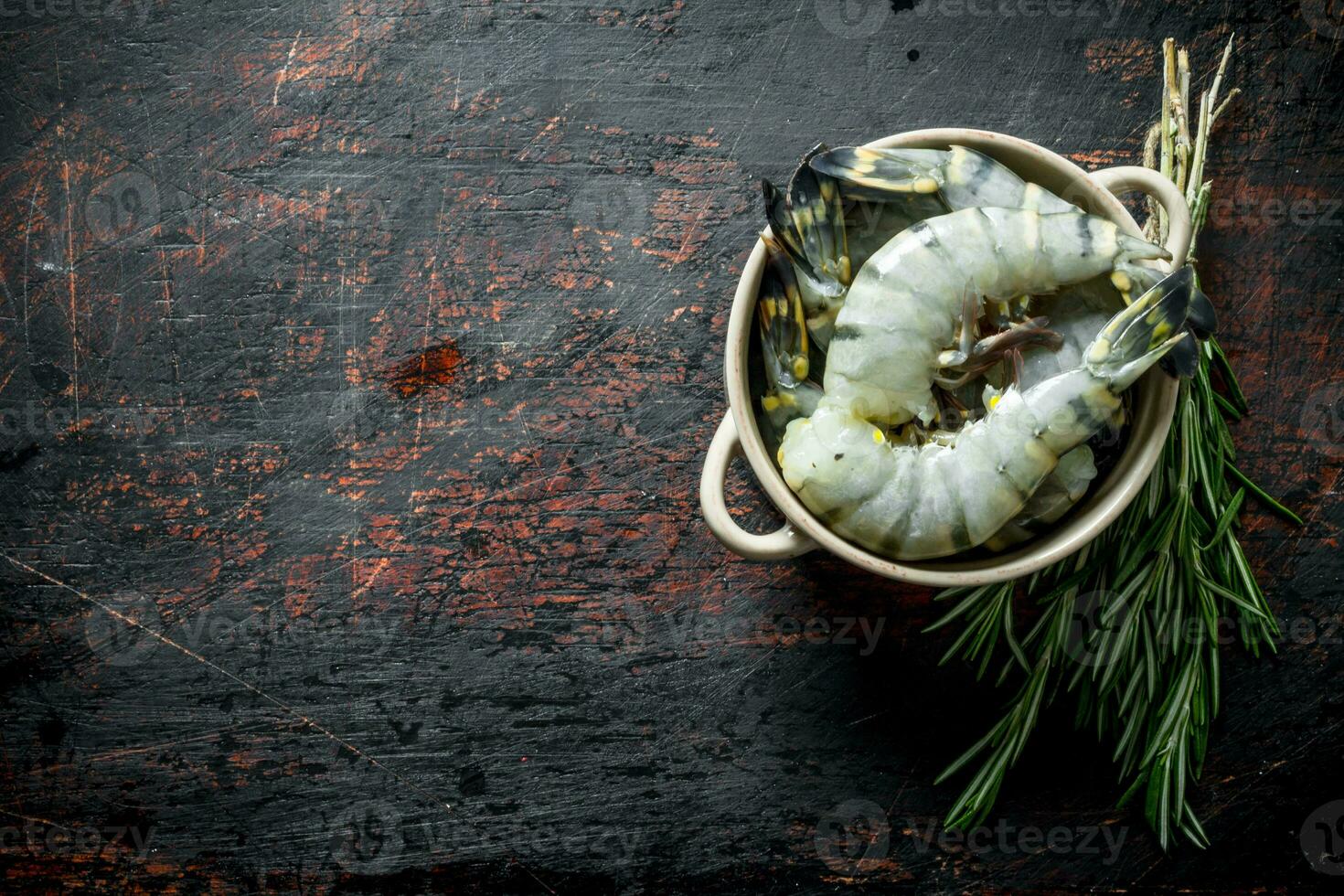 Fresh selected raw shrimps in bowl with rosemary. photo