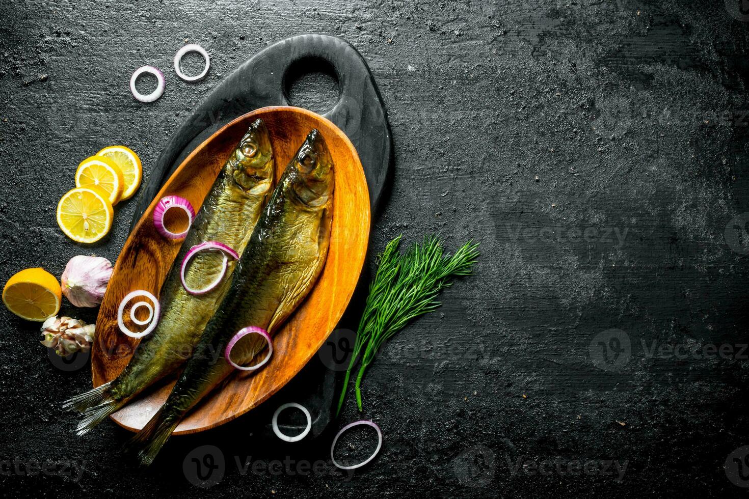 Smoked fish with dill, slices of lemon and onion. photo