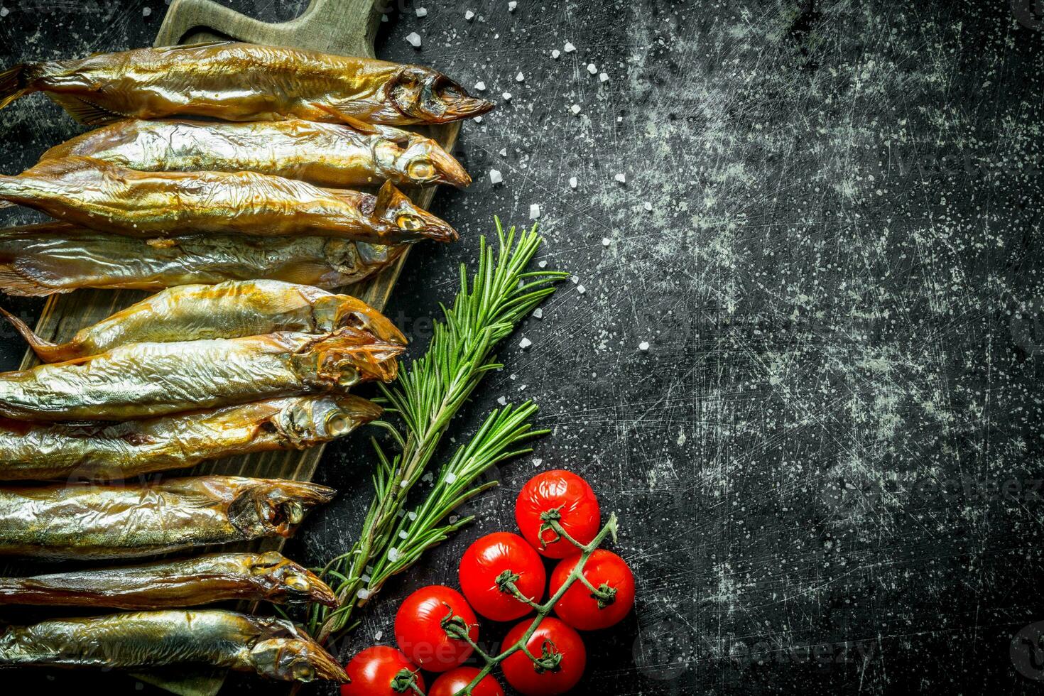 Delicious smoked fish with rosemary and tomatoes on a branch. photo
