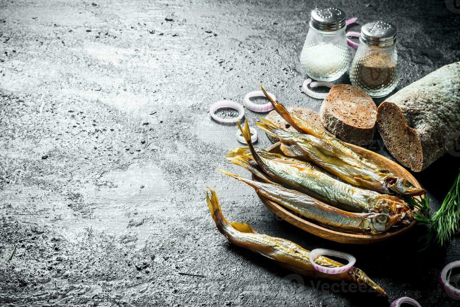 Smoked fish with sliced bread, spices and onion rings. photo