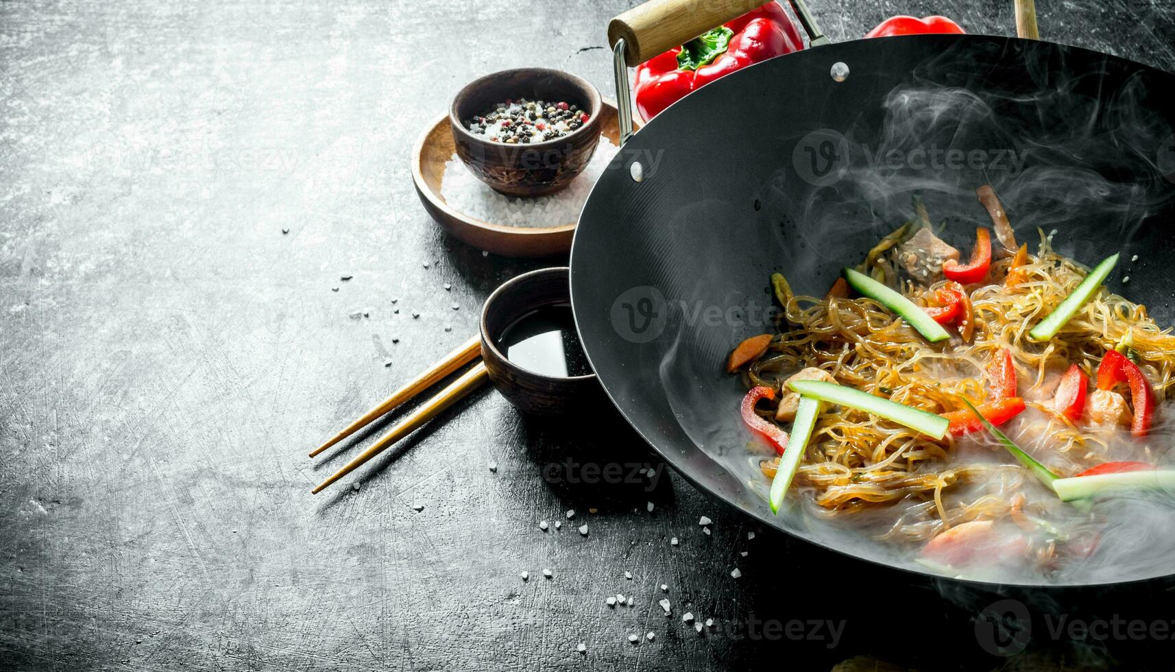 Hot cellophane noodles in a frying pan wok with bell peppers, cucumber and carrots. photo