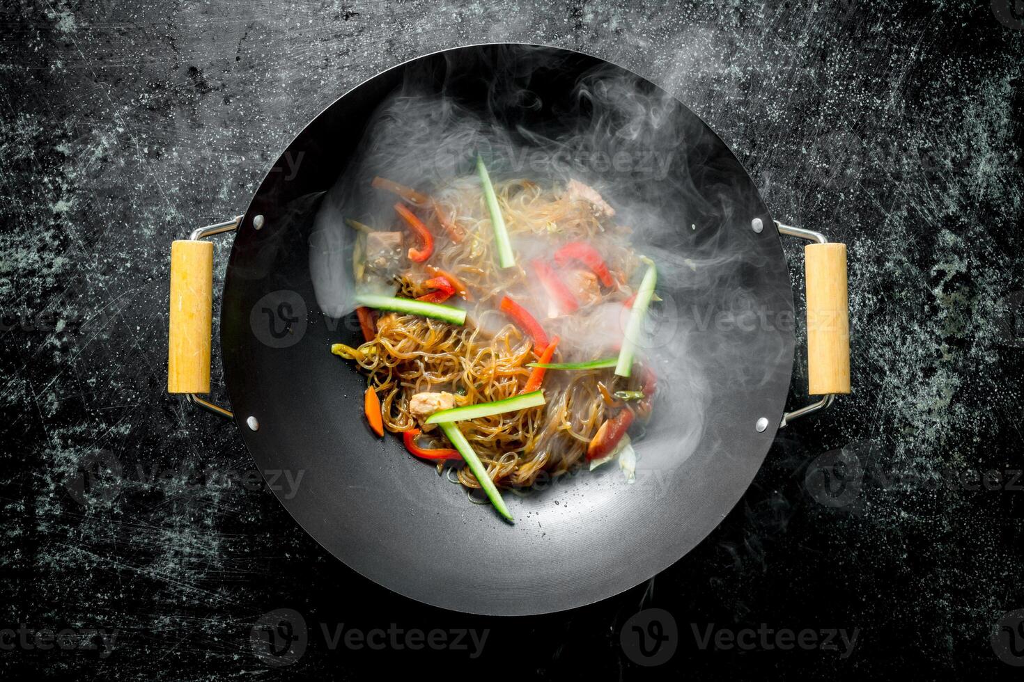 Hot cellophane noodles in a frying pan wok with bell peppers, cucumber and carrots. photo