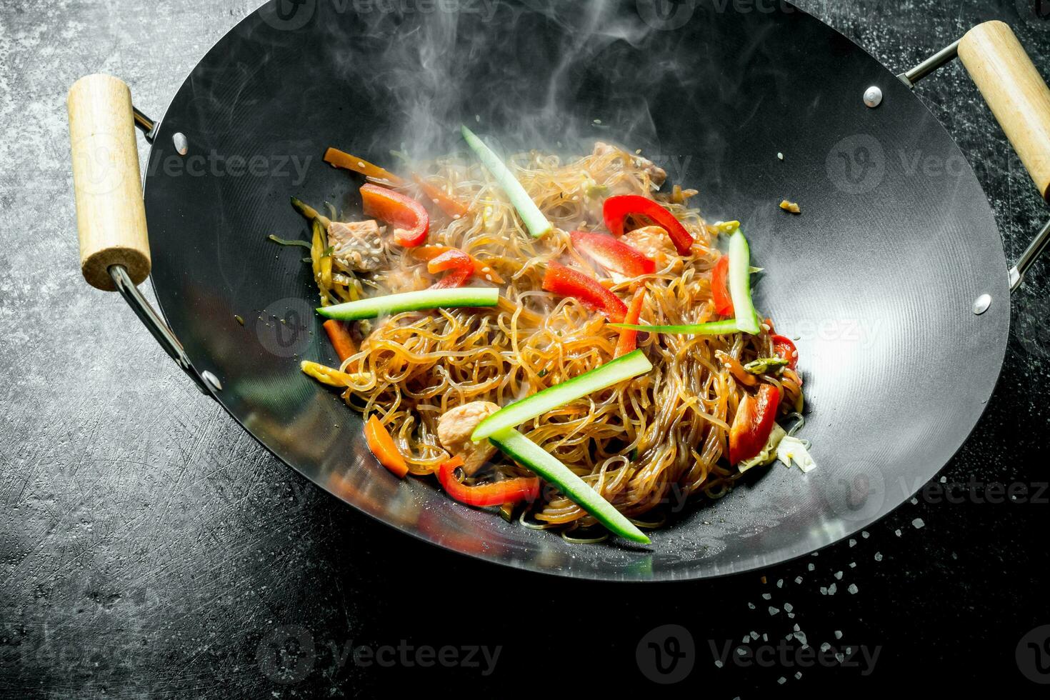 Hot cellophane noodles in a frying pan wok with bell peppers, cucumber and carrots. photo
