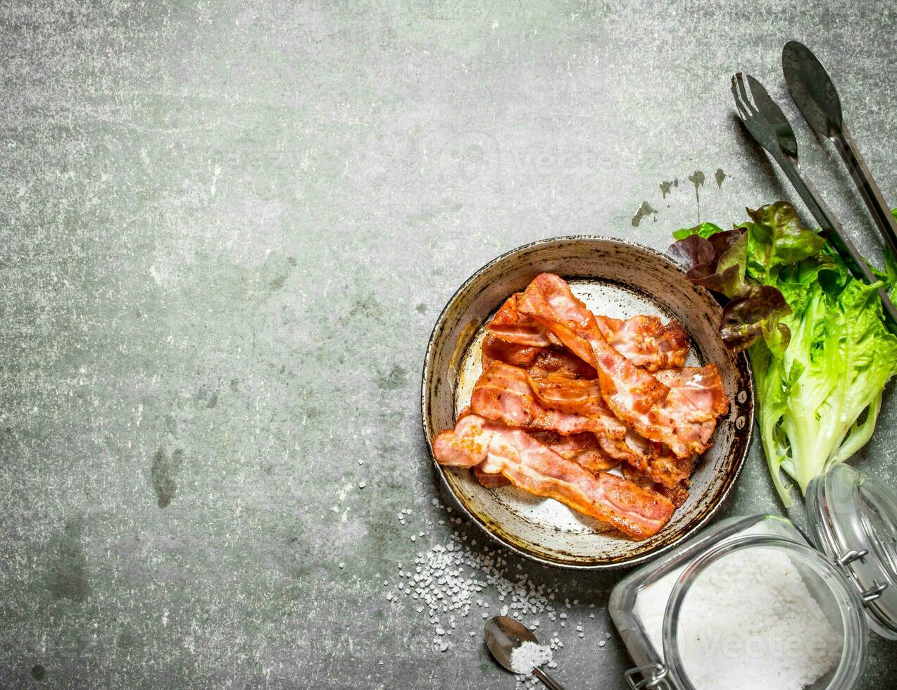 Bacon in a frying pan with salt and herbs. photo