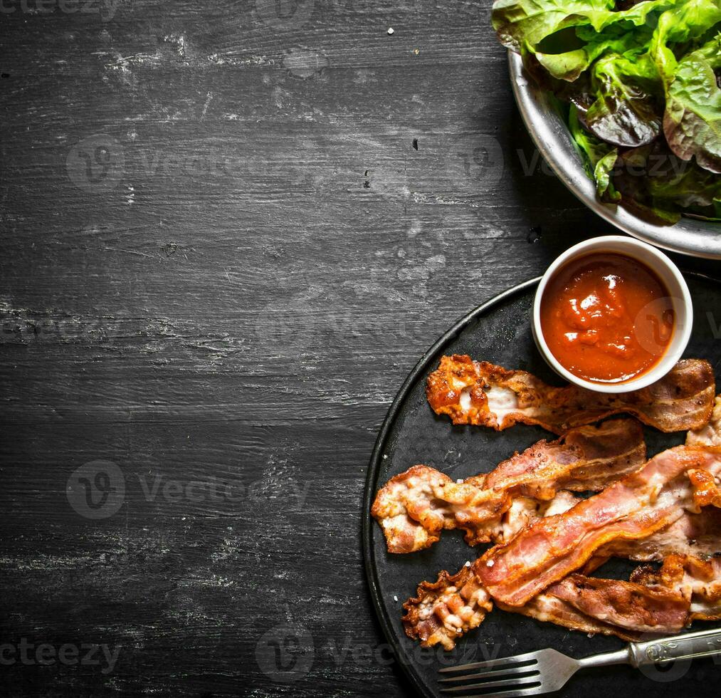 Fried bacon with sauce and greens. photo