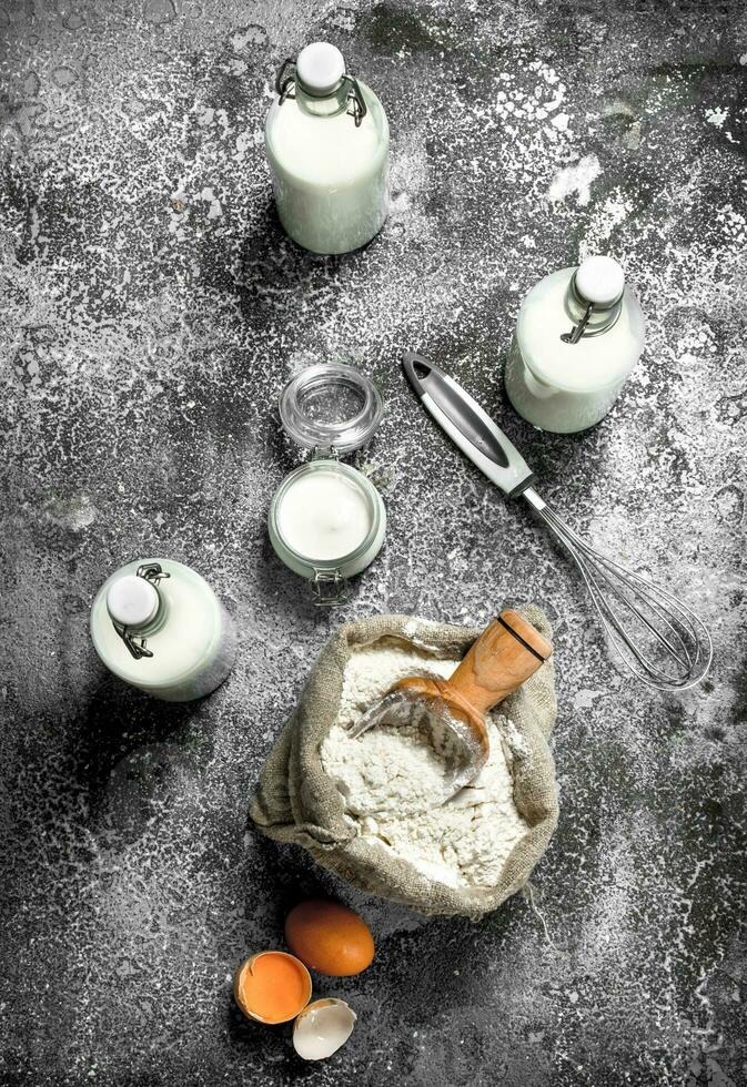 Baking background. Flour with fresh milk in bottles, sour cream and eggs. photo