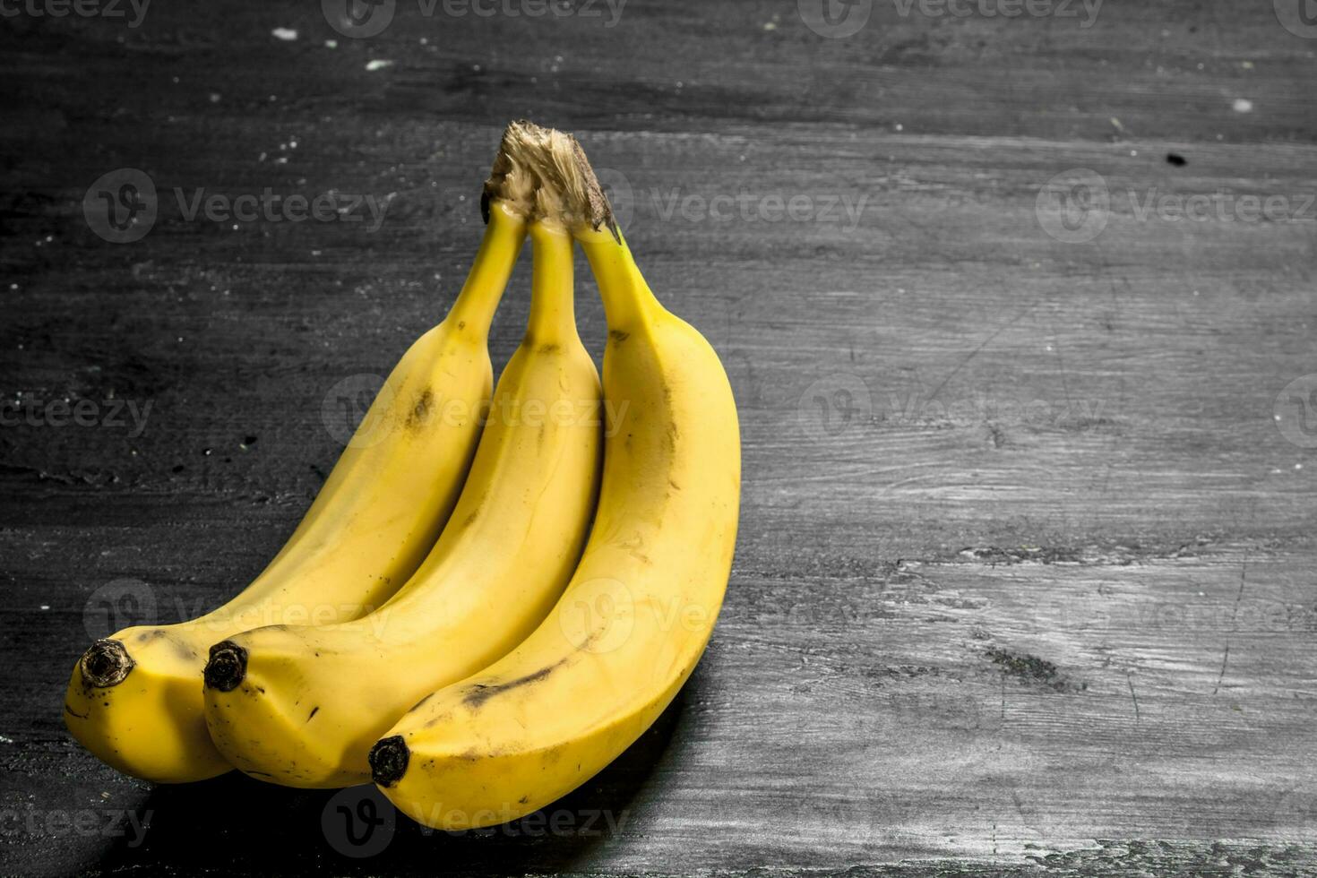 manojo de maduro plátanos en negro pizarra foto