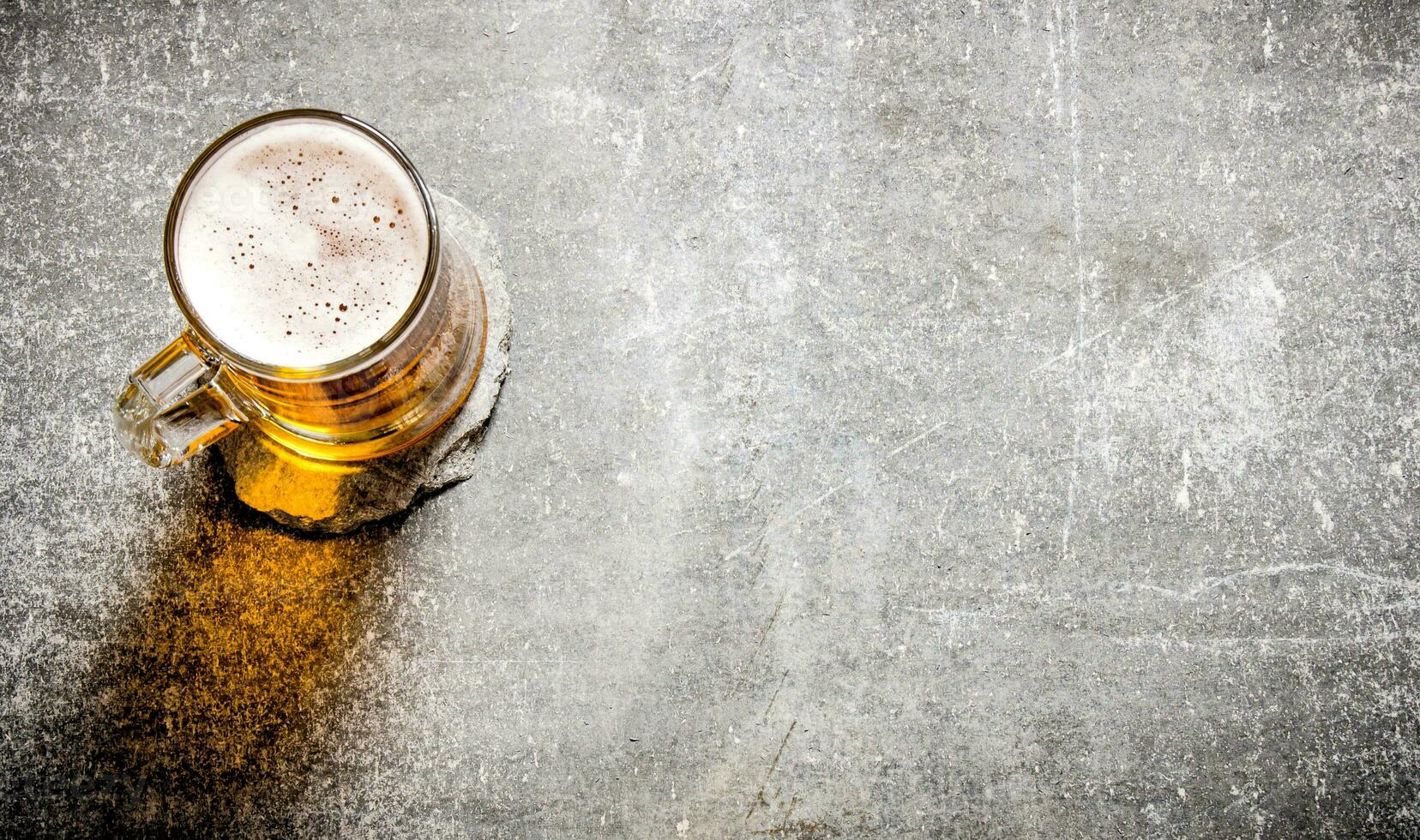 Beer in a glass on old stone surface. photo