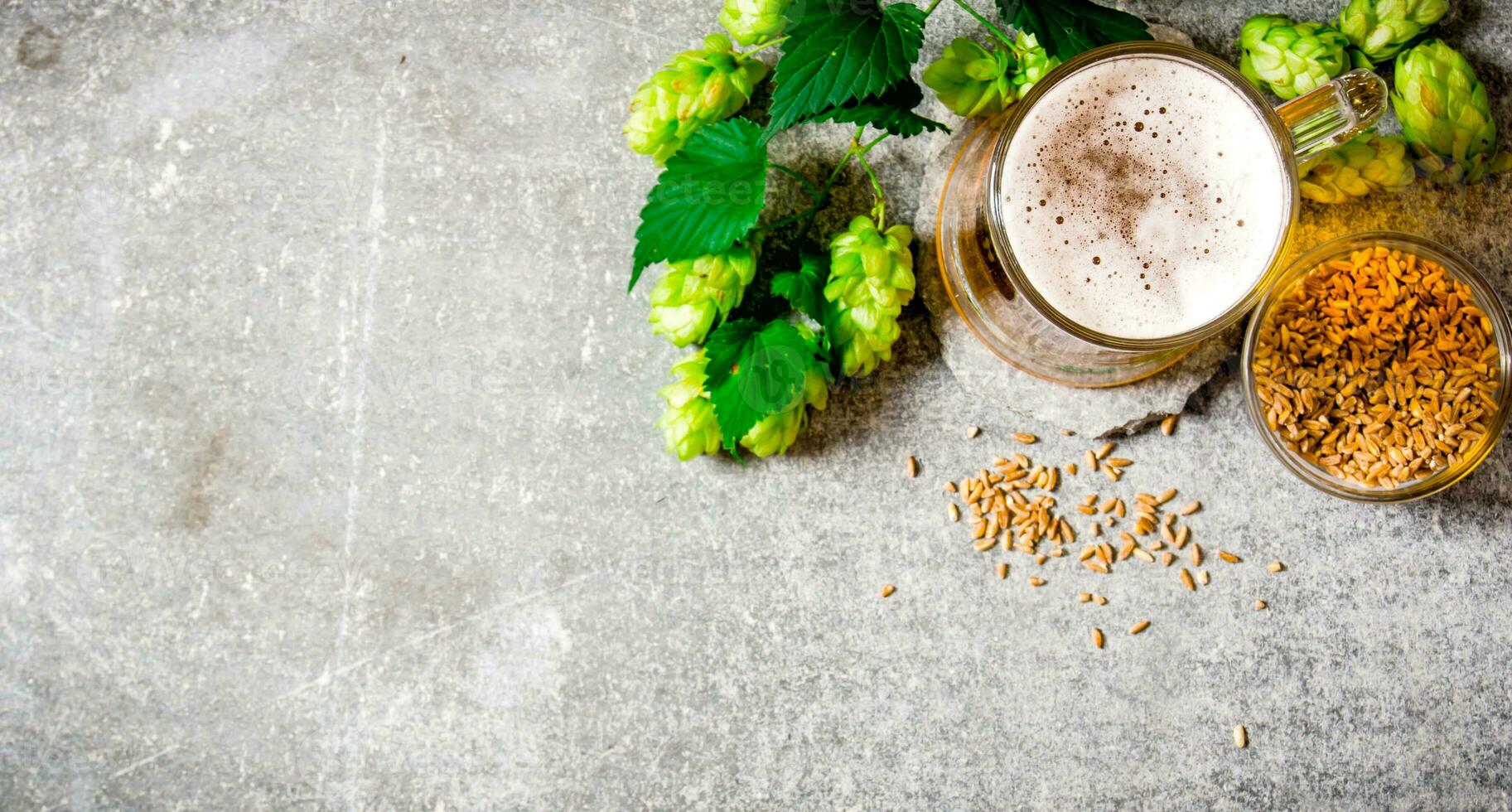 Beer, green hops and malt on stone surface. photo