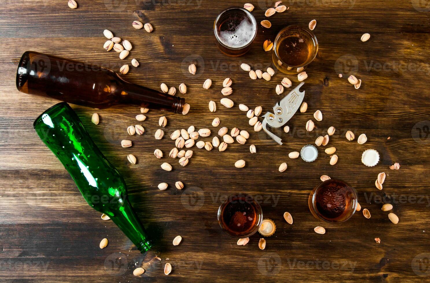 Four beers with pistachios on a wooden table. photo