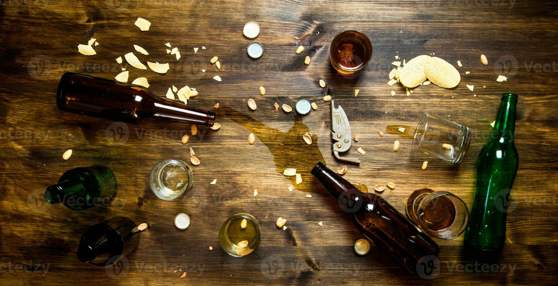 en el proceso de fiesta - derramado cerveza, botella tapas y sobrante papas fritas en el mesa. foto