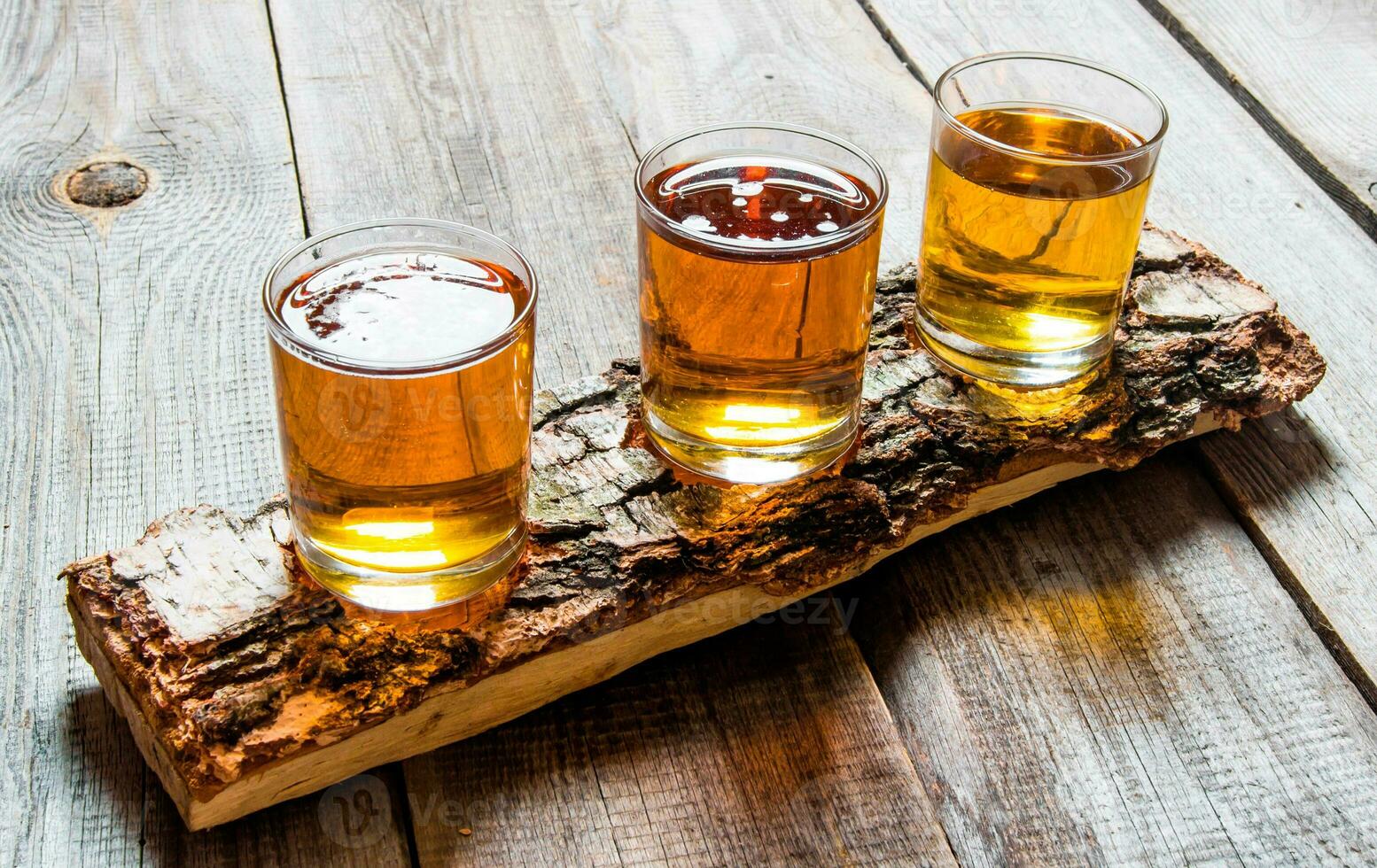 Tres cervezas en abedul pararse. en un de madera mesa. foto