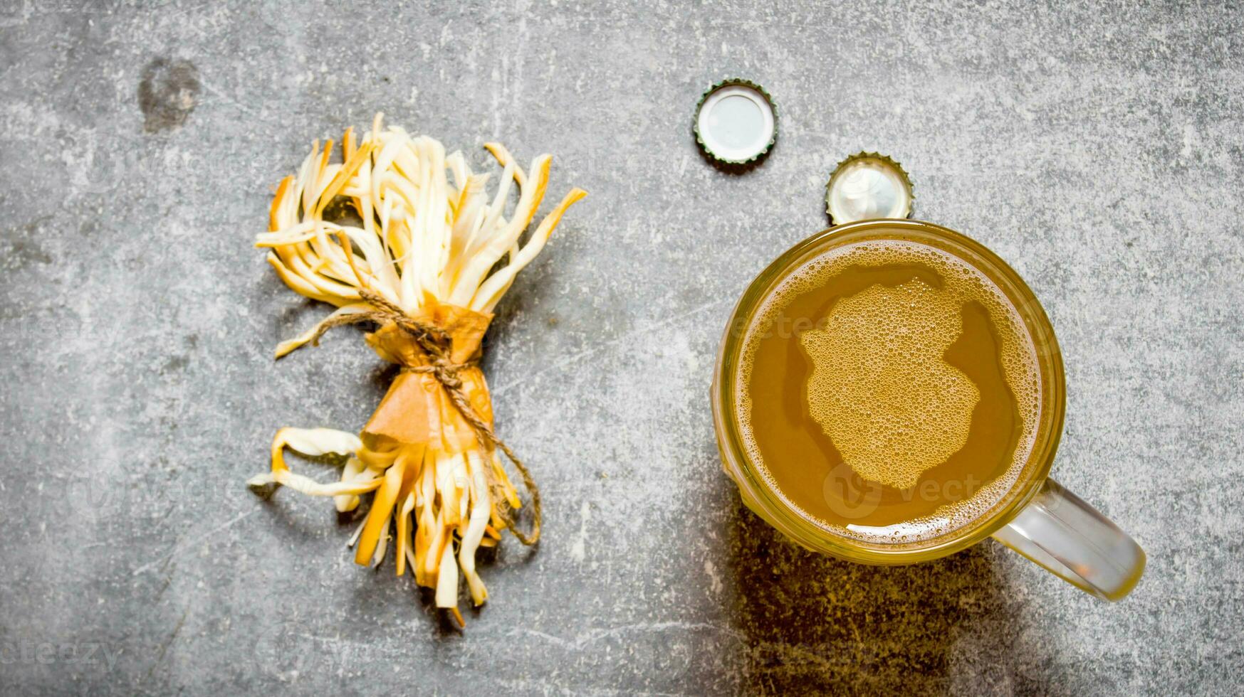 Glass of beer and salty cheese on stone background. photo