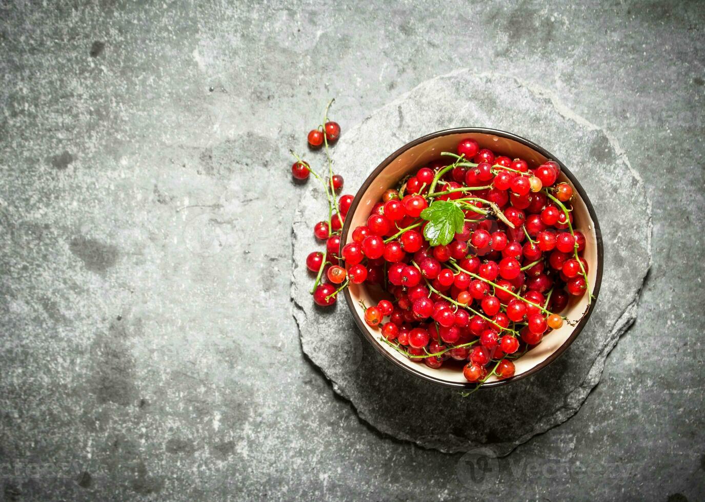 Red currant in the Cup. On stone table. photo