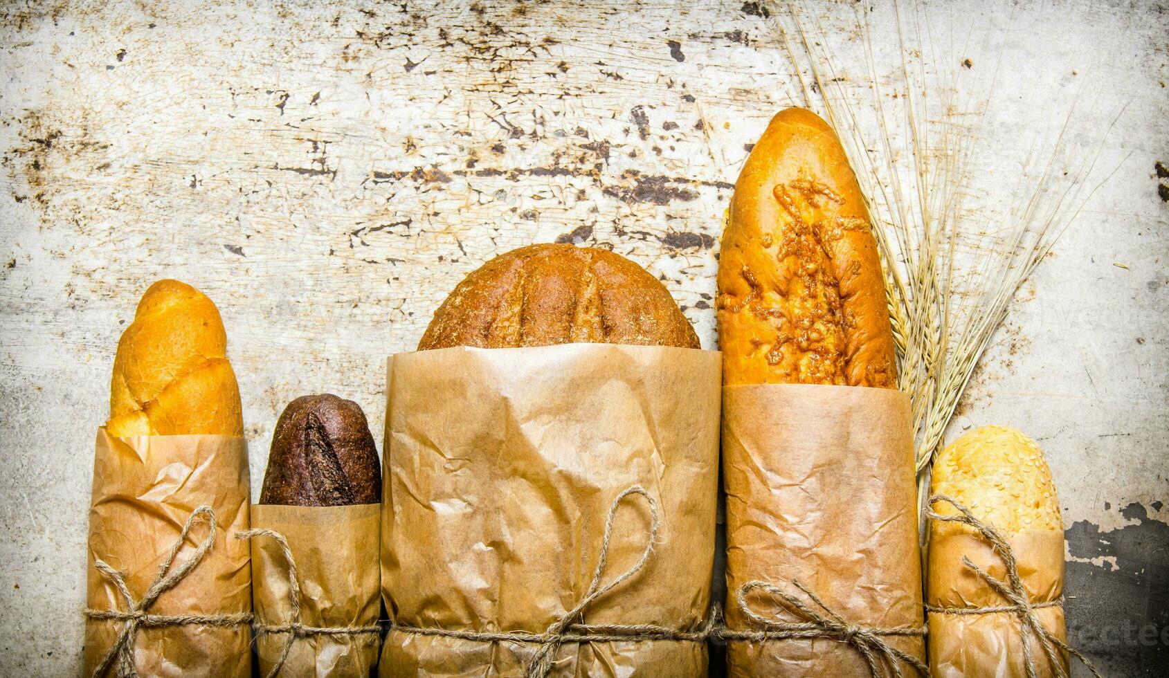 Fresh bread wrapped in paper. On rustic background. photo