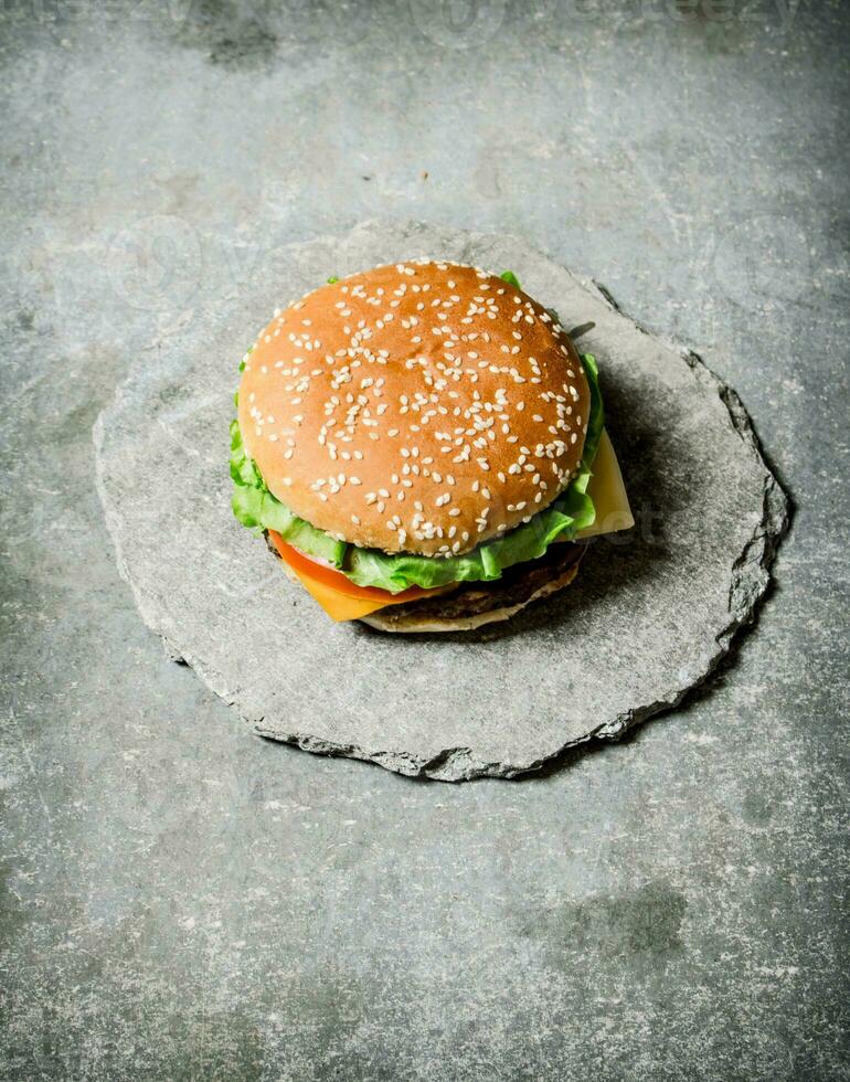Fresh Burger with cheese and meat on a stone stand. photo