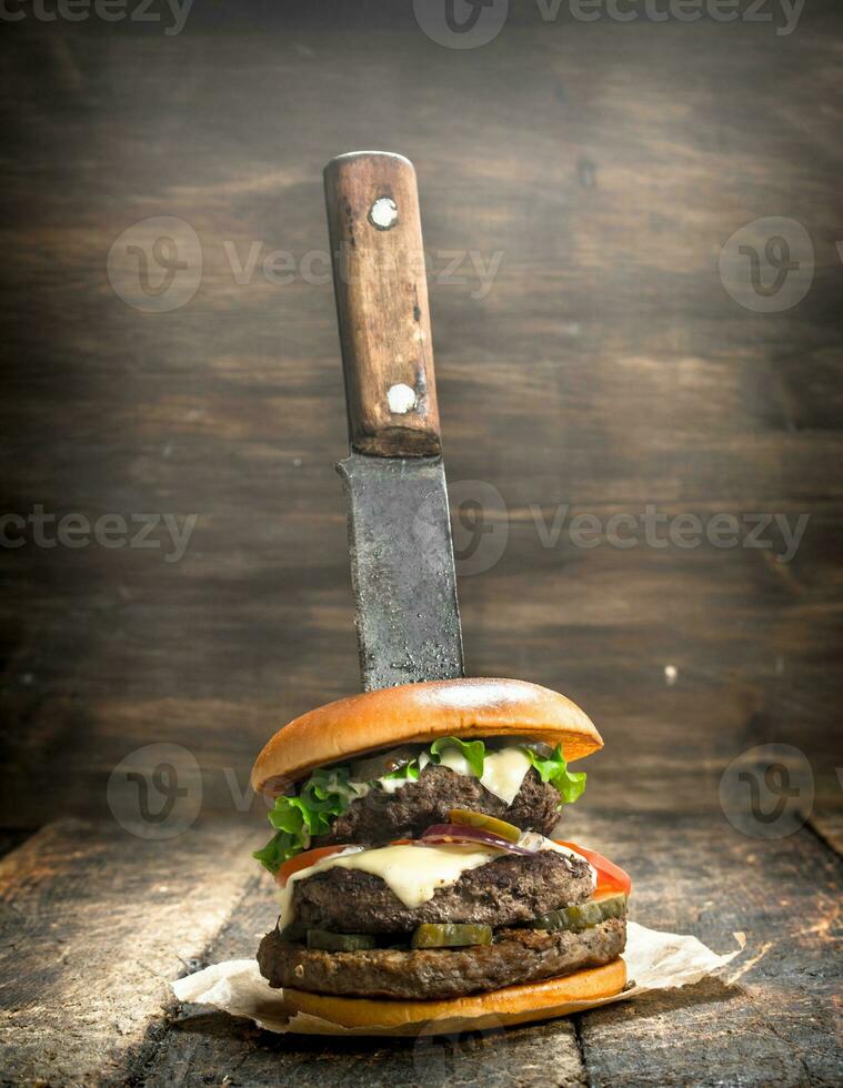 Fast food. A fresh burger made from beef and vegetables with a large knife. photo