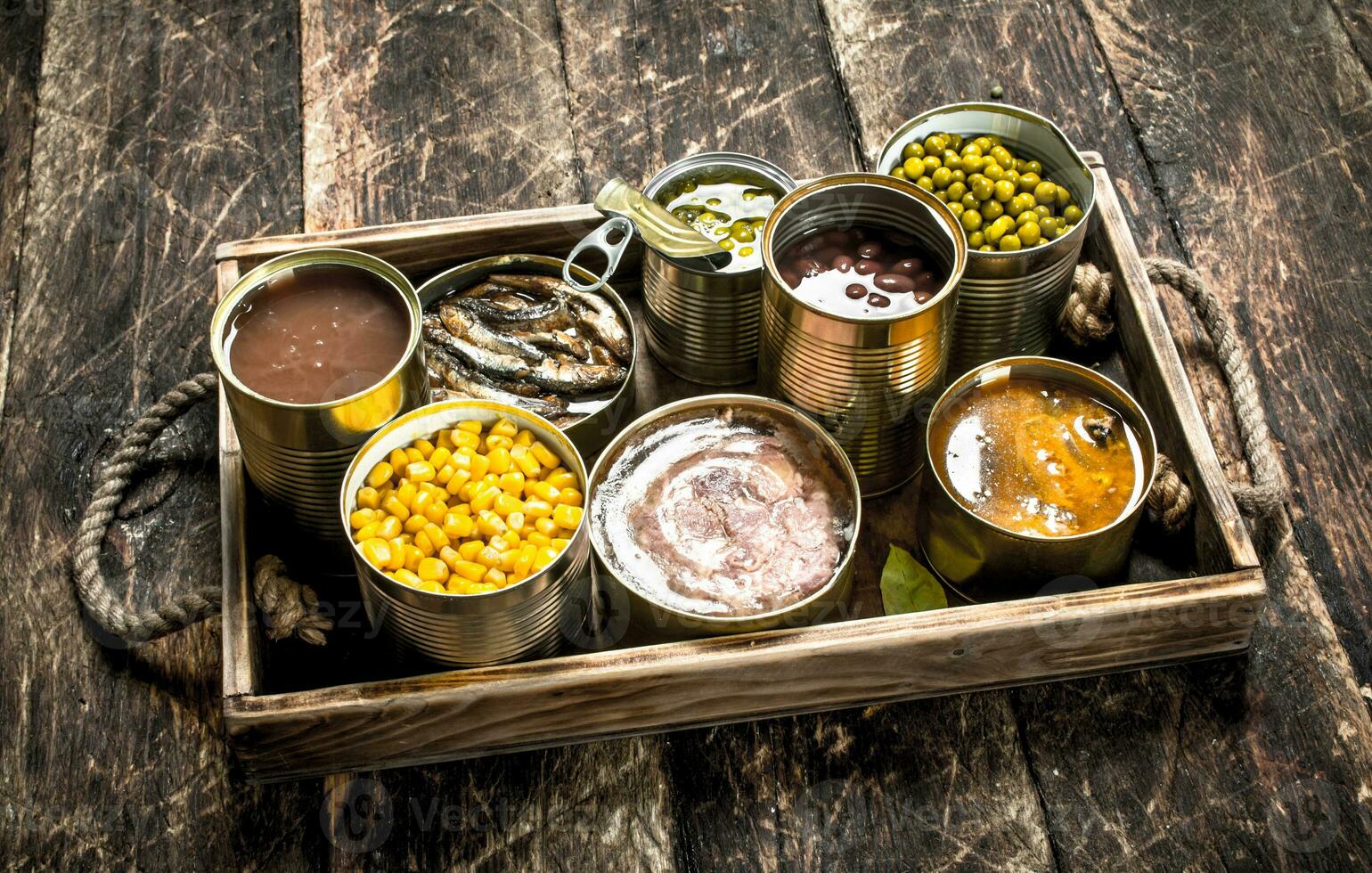 Various canned fruits, vegetables, fish and meat in tin cans on old tray. photo