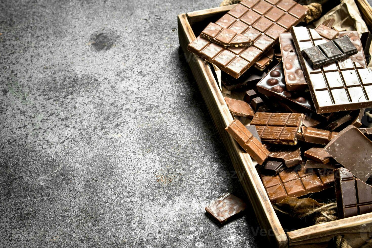 Broken chocolate bars on wooden tray. photo