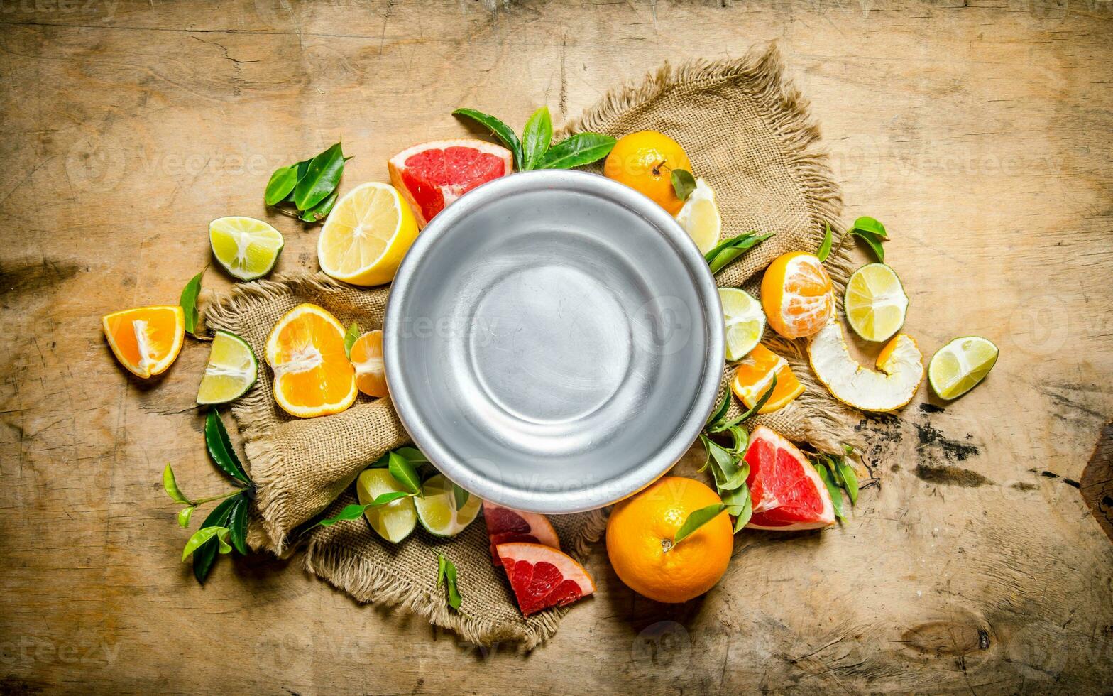 Empty the bowl of fruit around citrus - grapefruit, orange, tangerine, lemon, lime the old fabric. photo