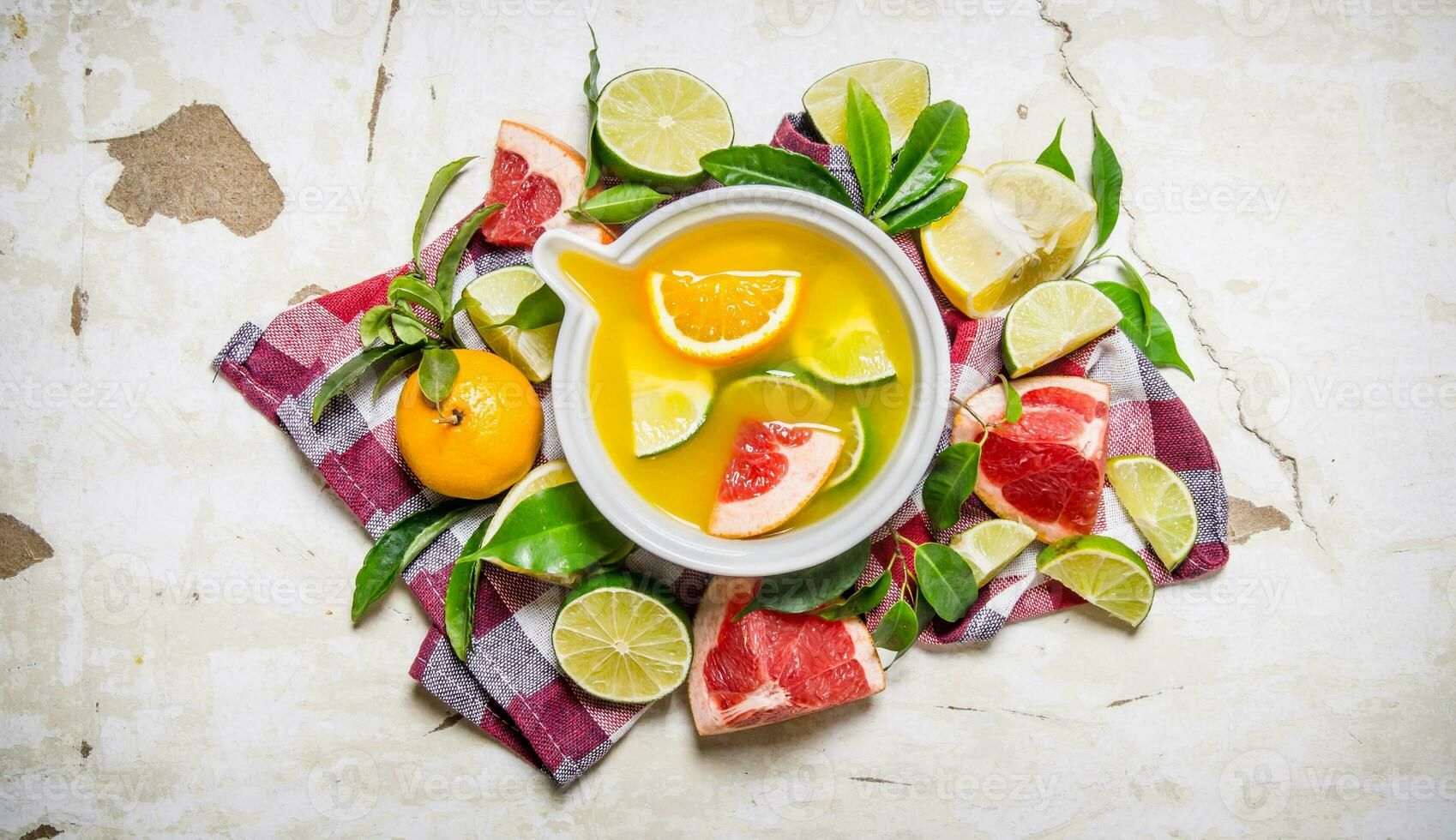 The juice from citrus fruits - grapefruit, orange, tangerine, lemon, lime in a cup with leaves. photo