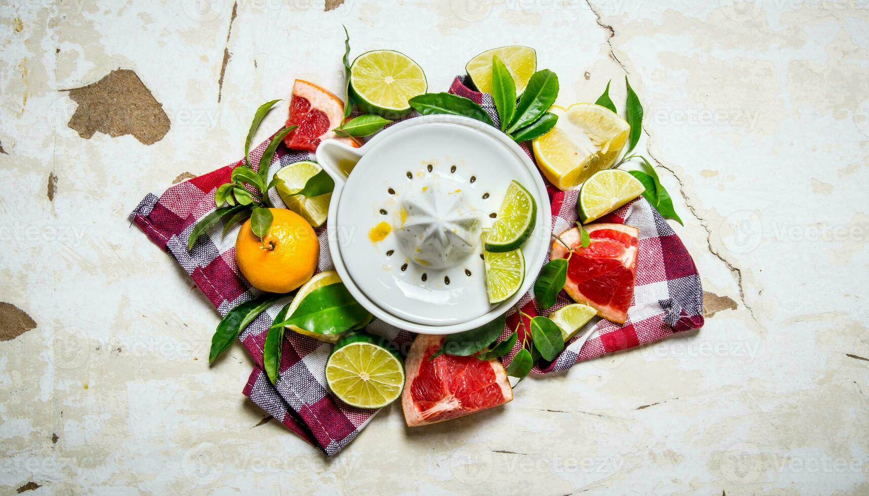 Juicer with citrus fruits - grapefruit, orange, tangerine, lemon, lime on the fabric. photo