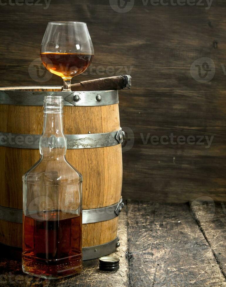 glass of cognac with a cigar on a barrel. photo