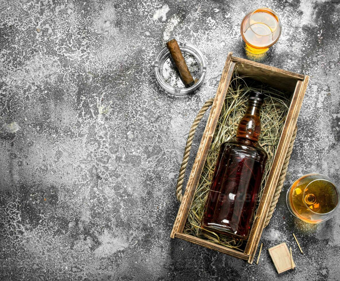 bottle of cognac in an old box with a cigar. photo