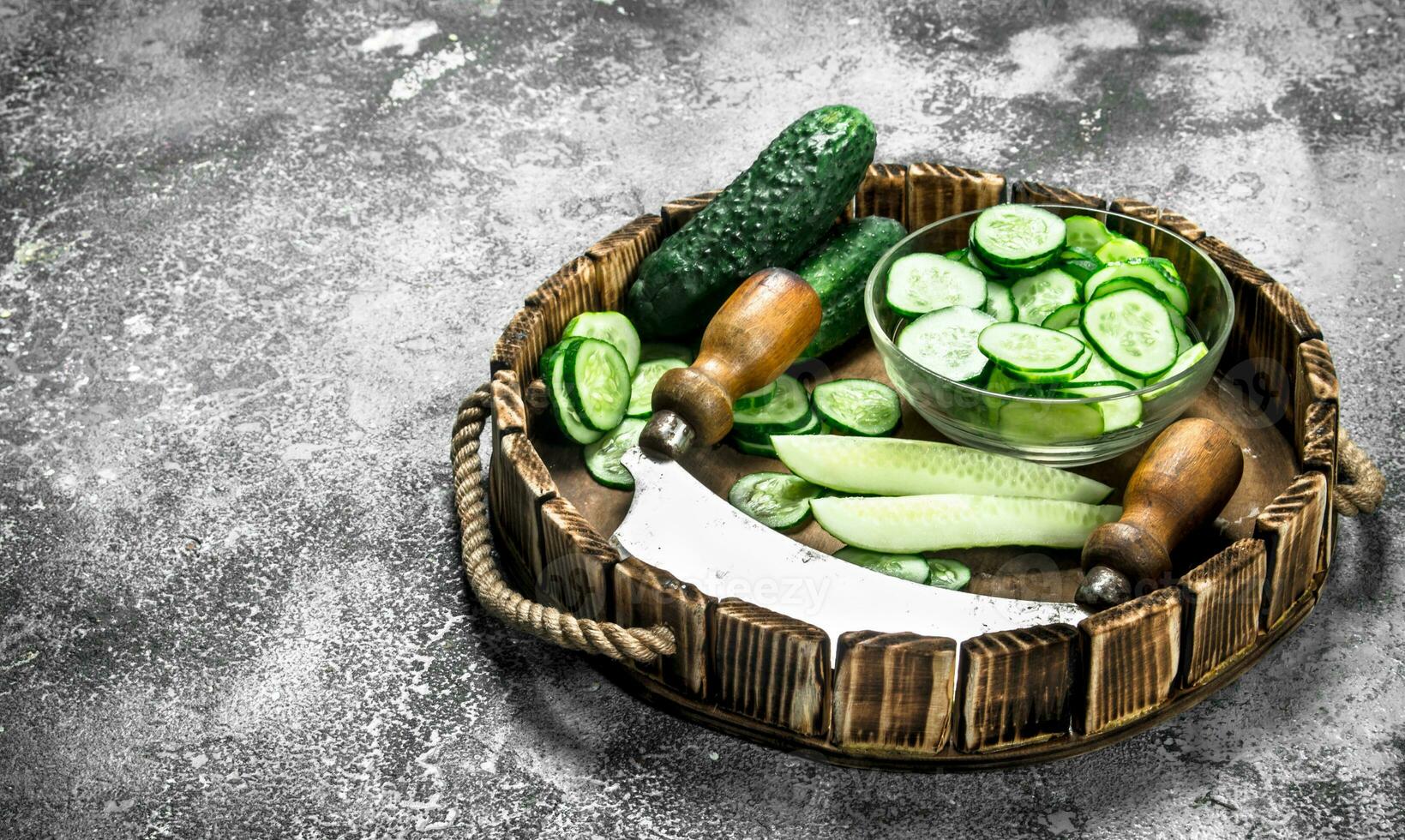 Fresh slices cucumbers on a wooden tray. photo