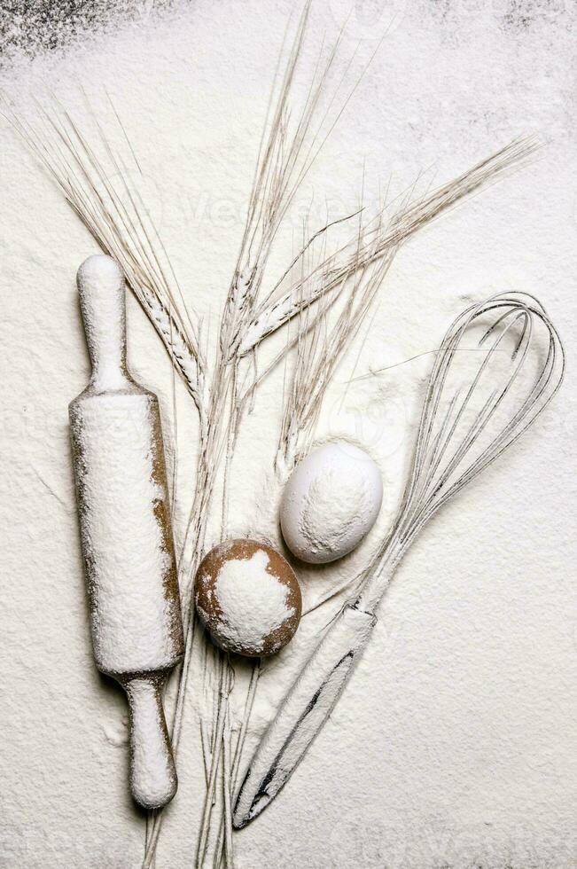 With the rolling pin whisk and ears of wheat in flour. photo