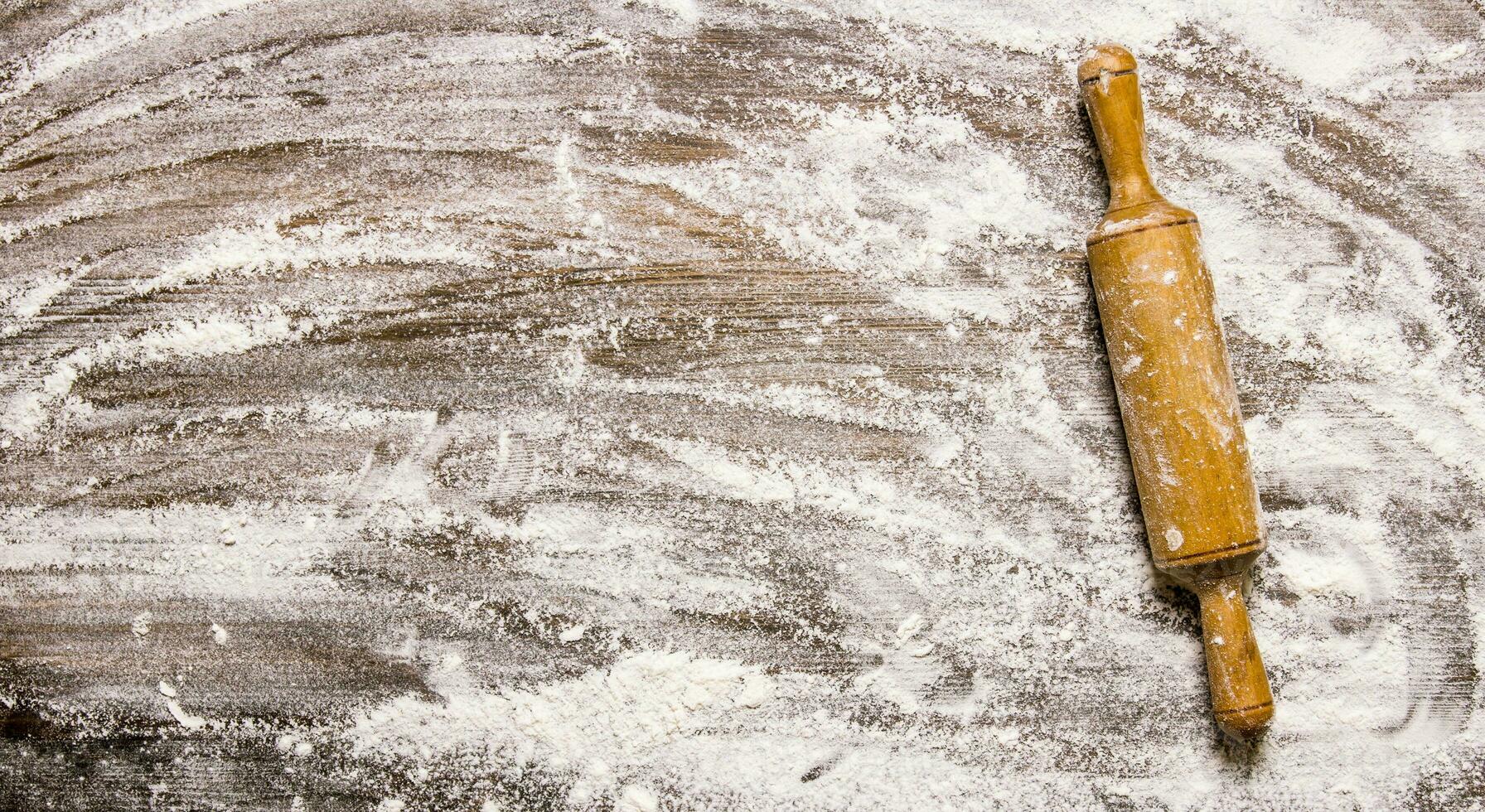The rolling pin with flour on wooden table. photo