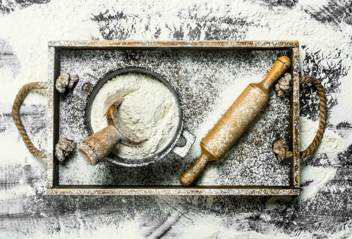 Flour in a bowl with rolling pin in a wooden box. photo