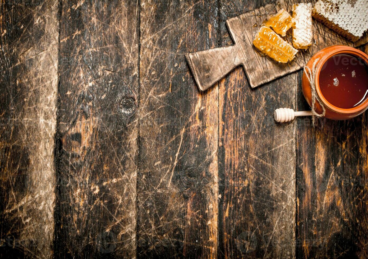 Honey pot and honeycomb with a wooden spoon. photo