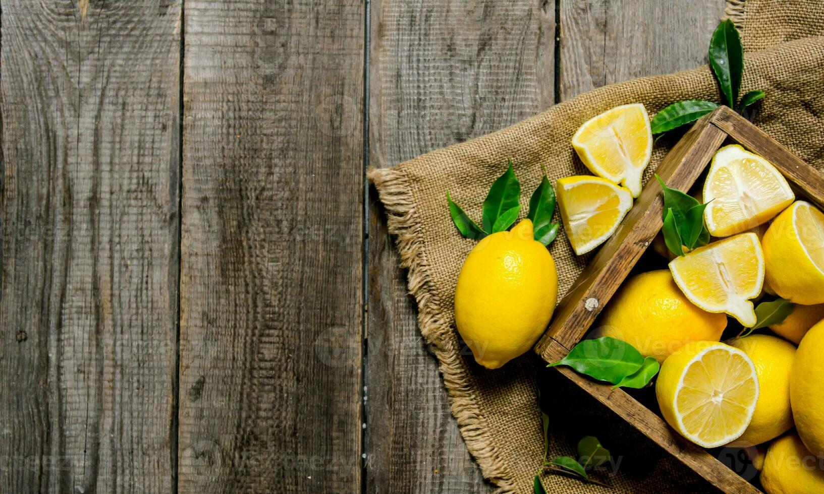Lemons with leaves in a box on the fabric . photo