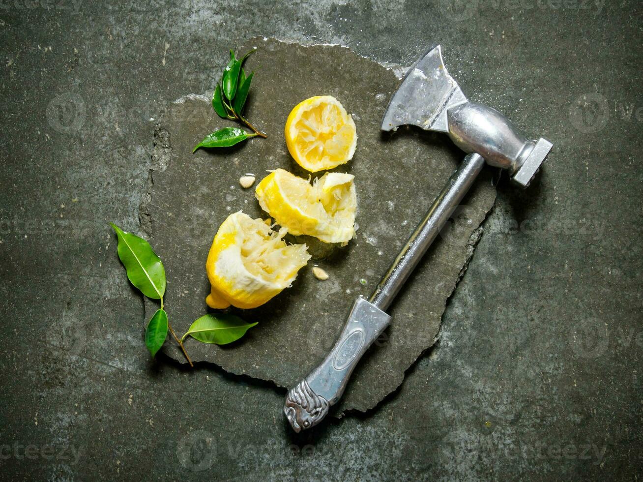 Axe with lemon and leaves on a stone stand. photo