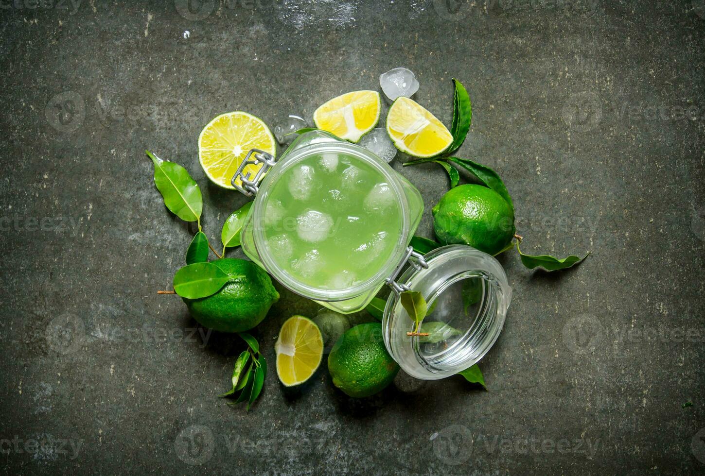 Lime background. The juice from the limes with ice and sliced limes around . photo