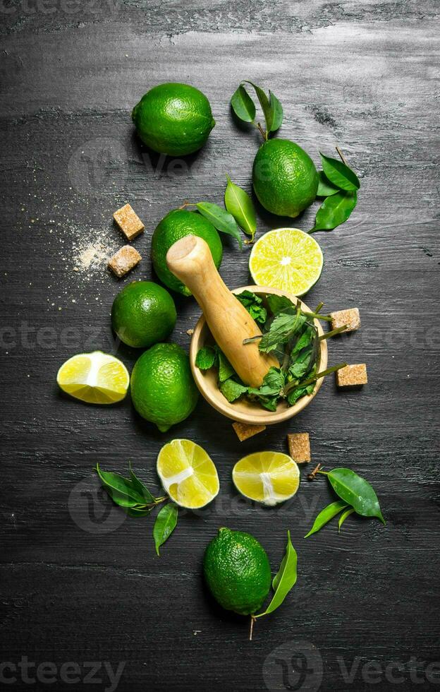 Lime background. The mortar with mint, sugar , lime slices and leaves . photo