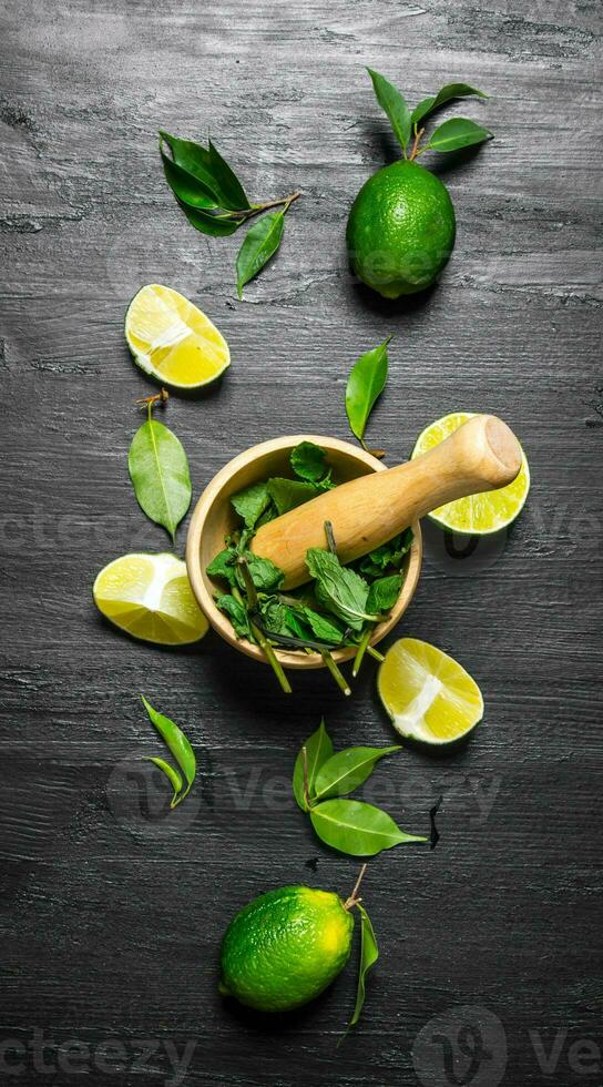 Lime background. The mortar with mint , lime slices and leaves . photo