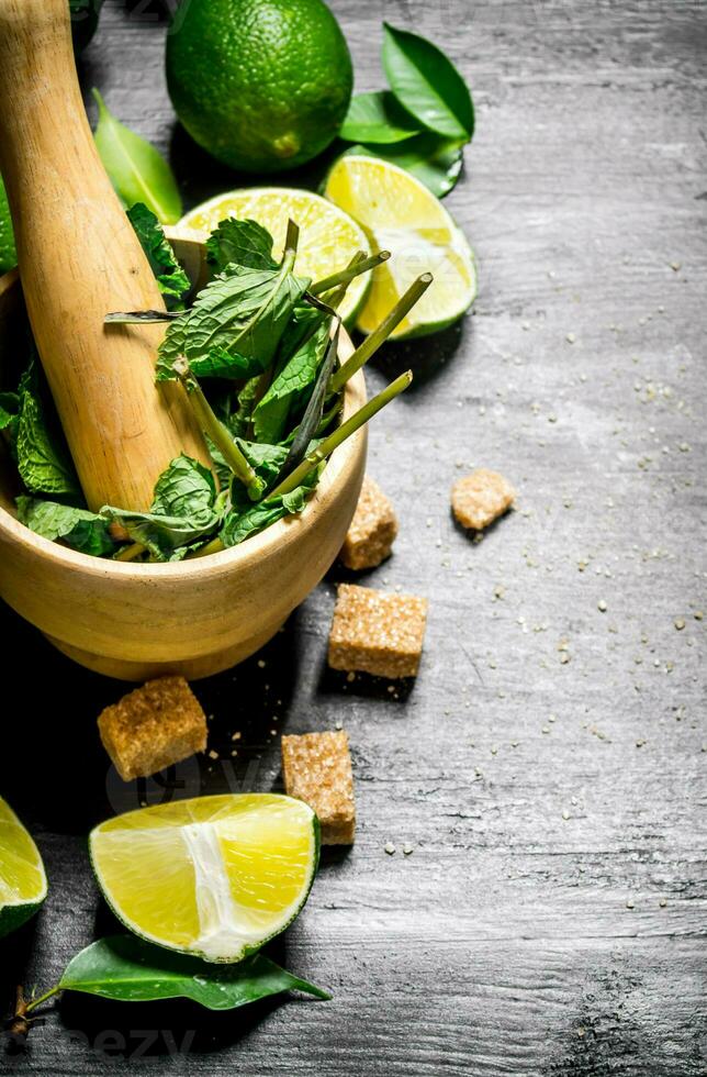 Lime background. The mortar with mint, sugar , lime slices and leaves . photo