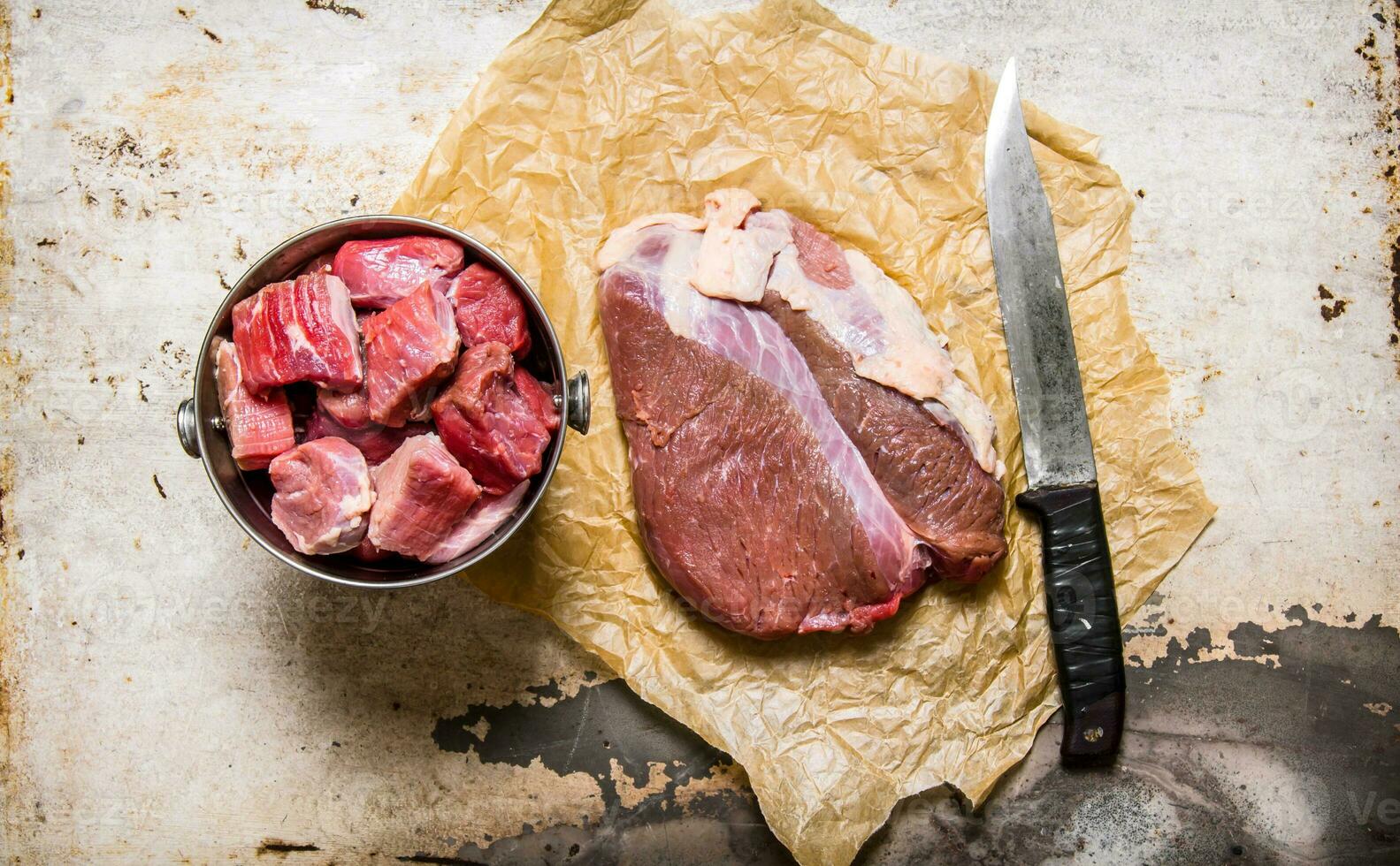 Cutting fresh raw meat on paper. On rustic background. photo