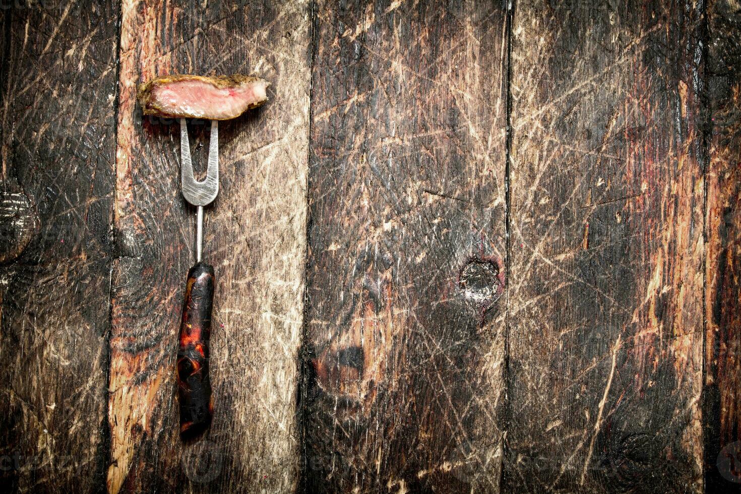 Meat grill. A piece of pork grilled on a fork . On the old wooden table. photo