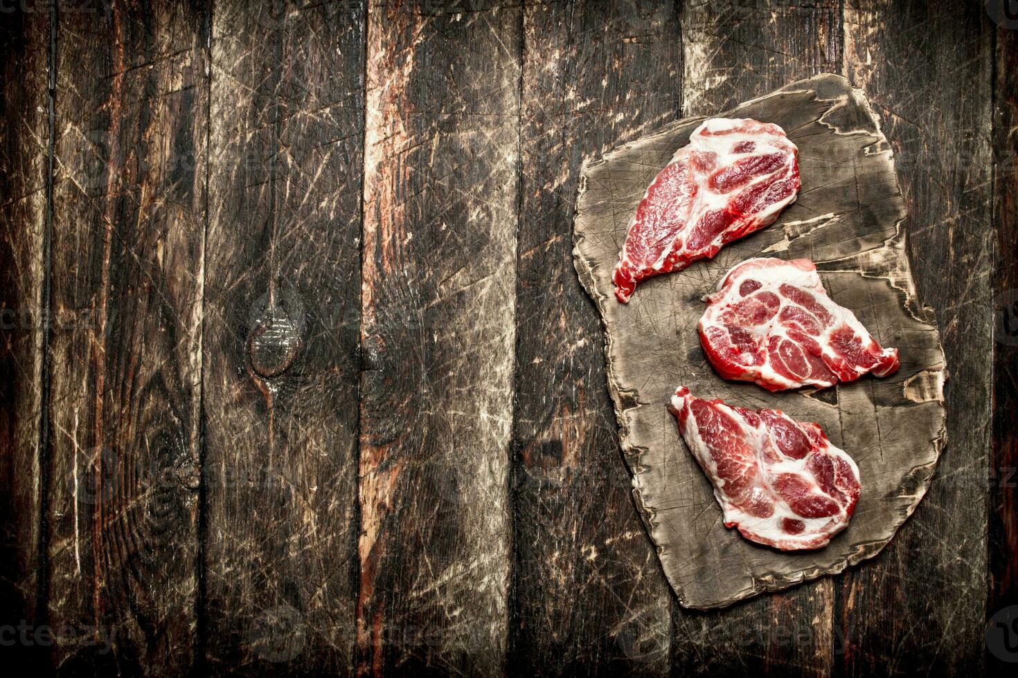 Raw meat background. Pieces of meat on the old Board. On wooden background. photo