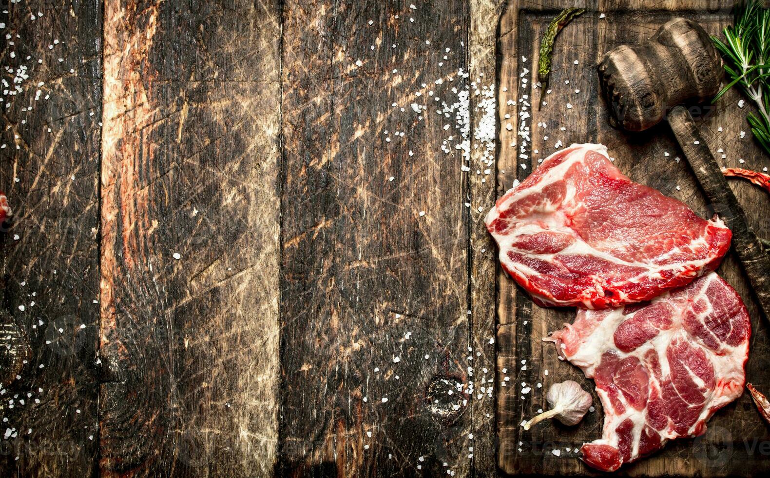 Raw meat background. Pieces of raw steak with spices and herbs. On wooden background. photo