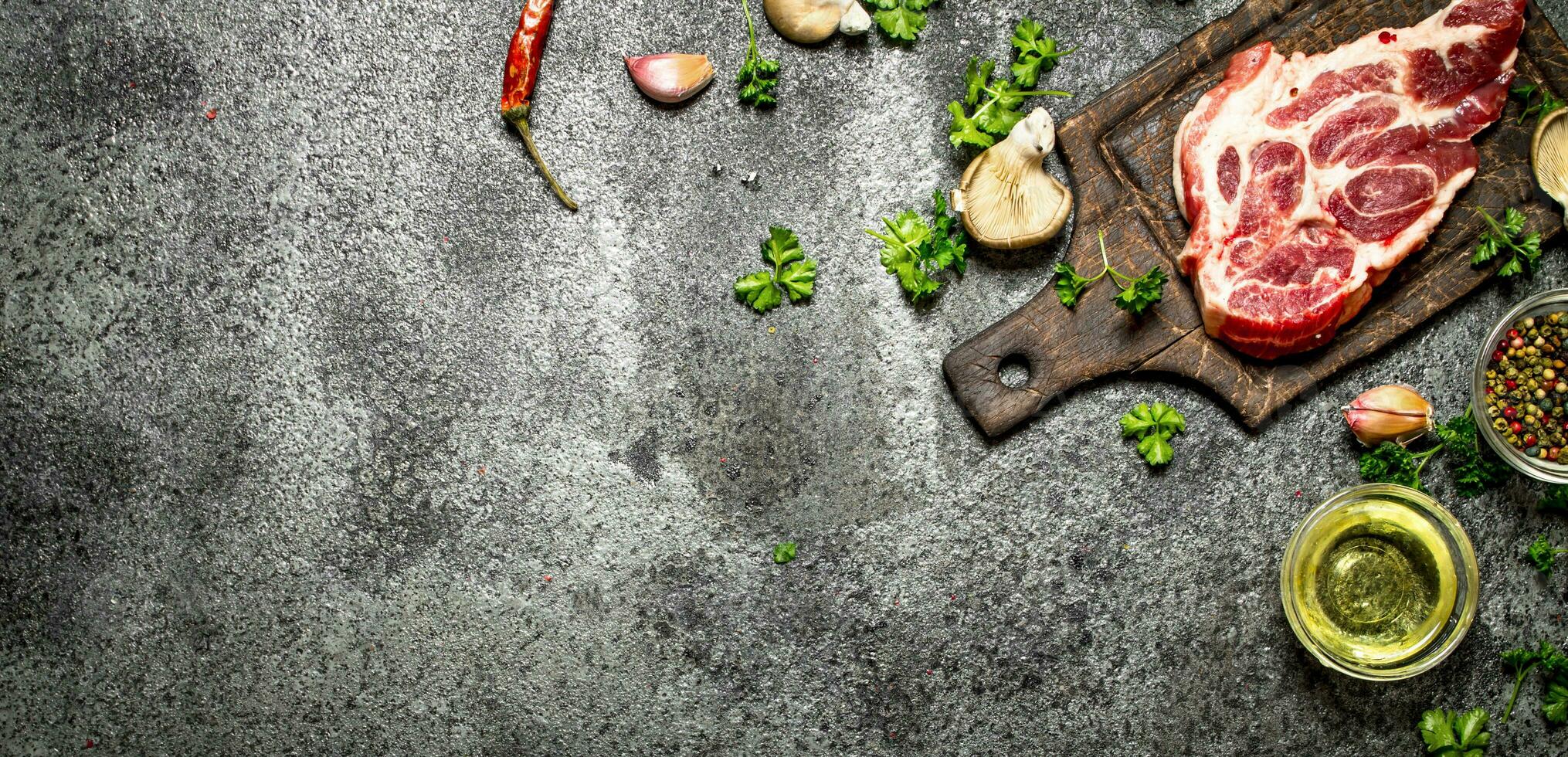 Raw meat background. A piece of Raw pork chops with fragrant spices and fresh herbs. On rustic background. photo