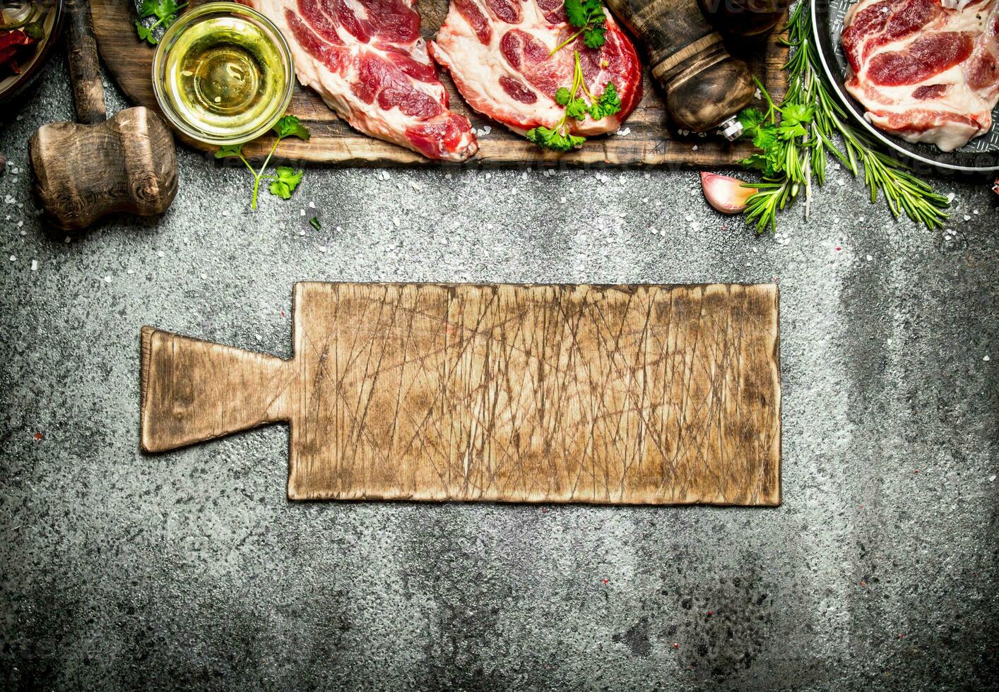 Raw meat background. Raw steak with herbs and spices on the old Board. On rustic background. photo