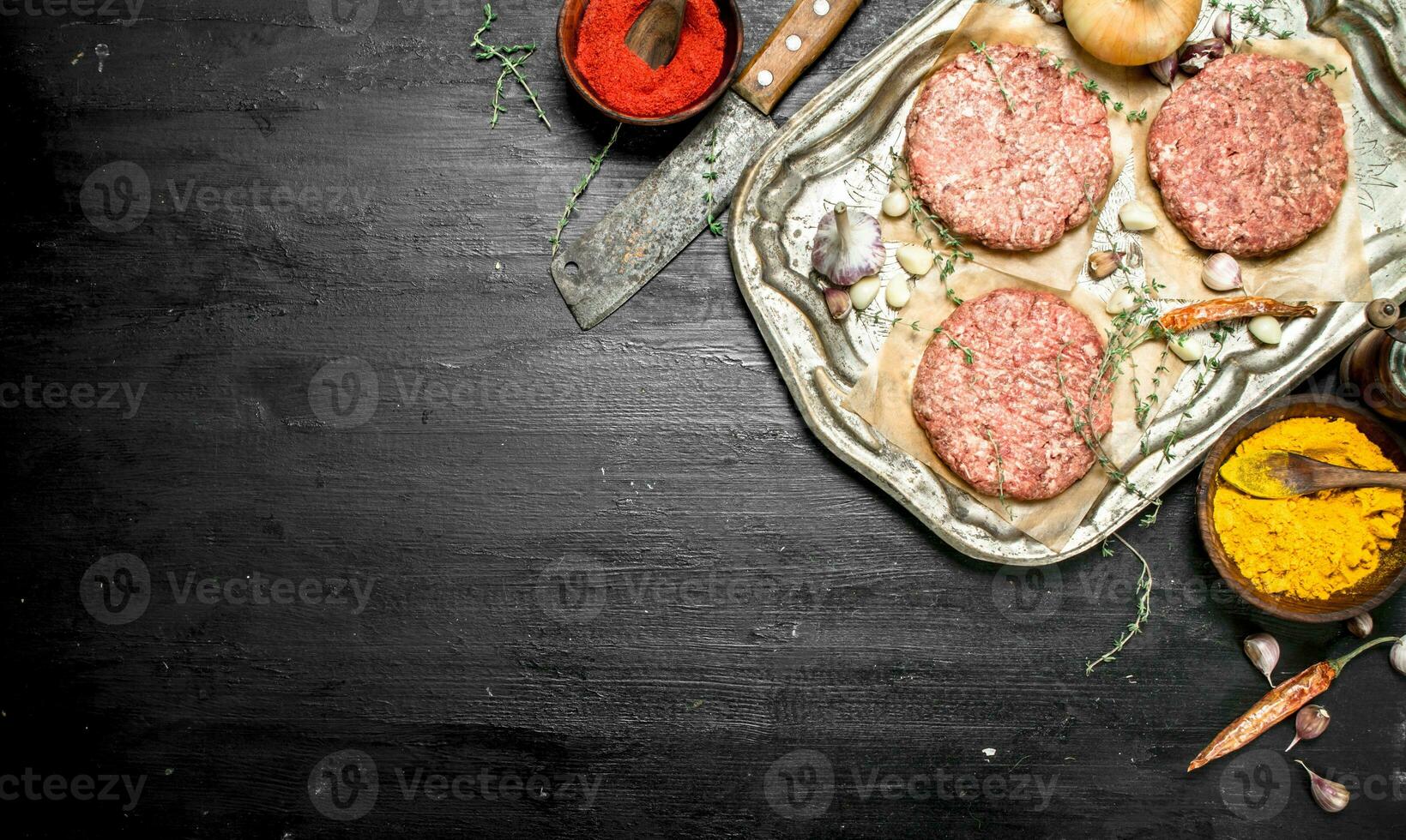Raw burger with garlic and spices on a steel tray. photo