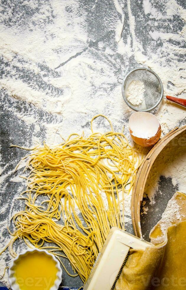 Cooking noodles. The pasta maker with strainer, eggs and flour. photo